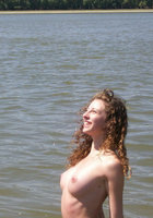 Молодая кудряшка купается в реке в одних трусах 12 фотография
